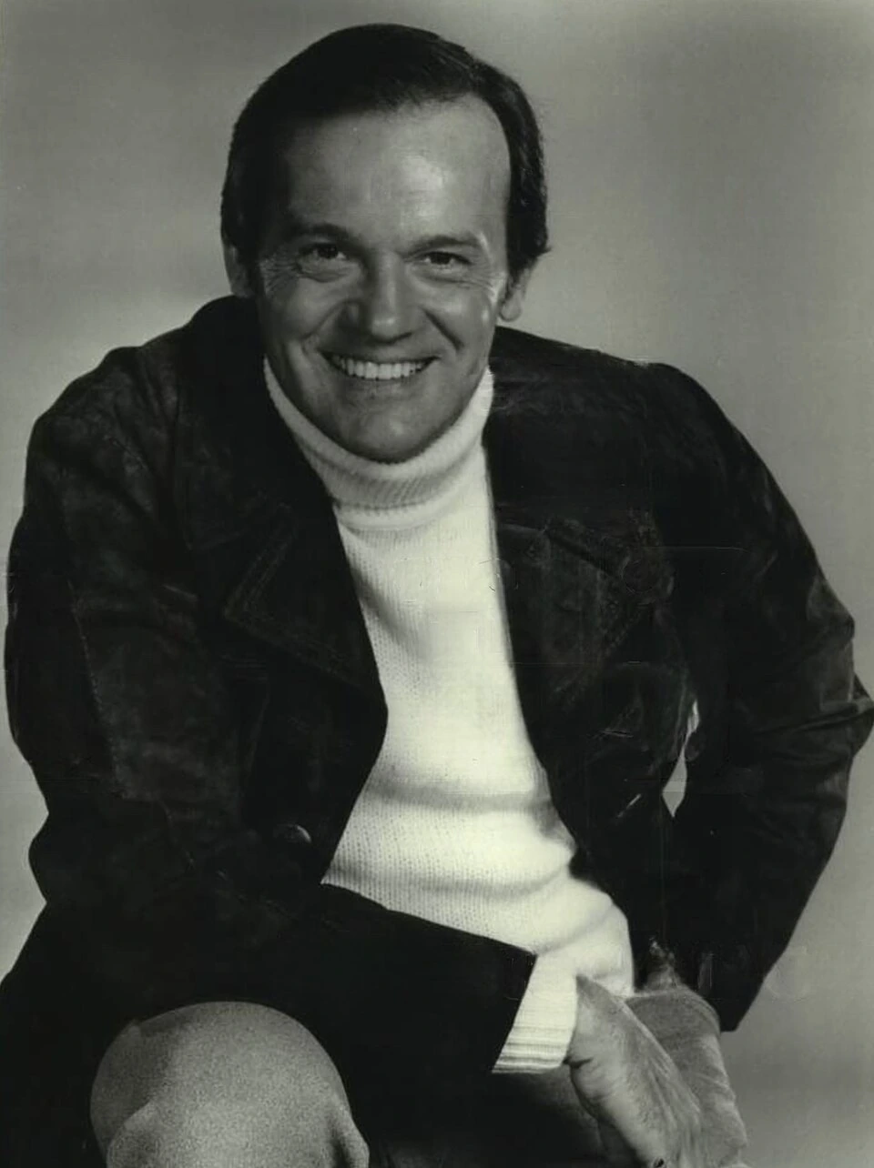 Black-and-white portrait photo of actor John S. Ragin smiling in a jacket and turtleneck.